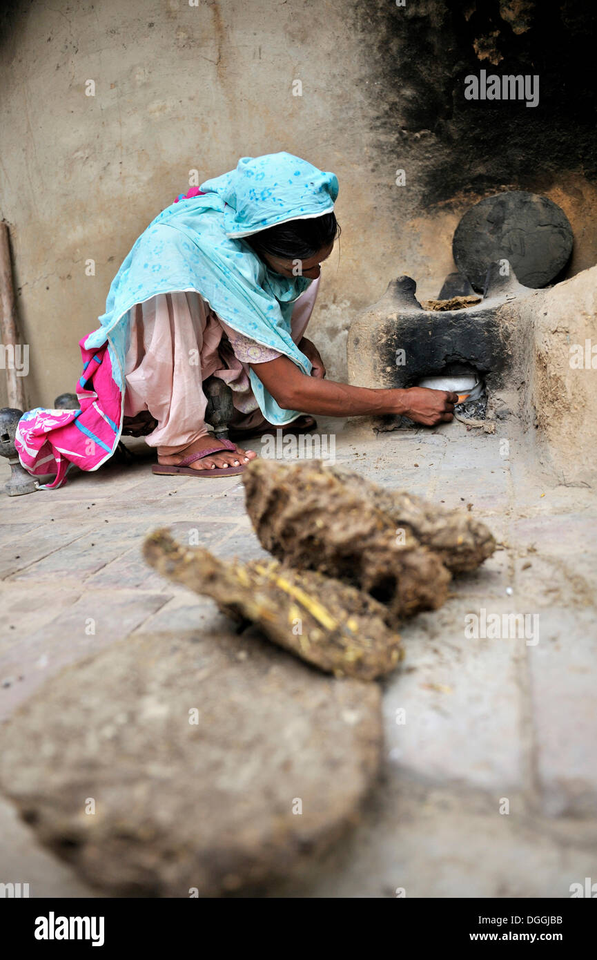 Frau zünden ein Feuer mit getrockneten Kuh dung, lebt und arbeitet sie mit ihrer Familie unter sklavereiähnlichen Praxis der Schuldknechtschaft Stockfoto