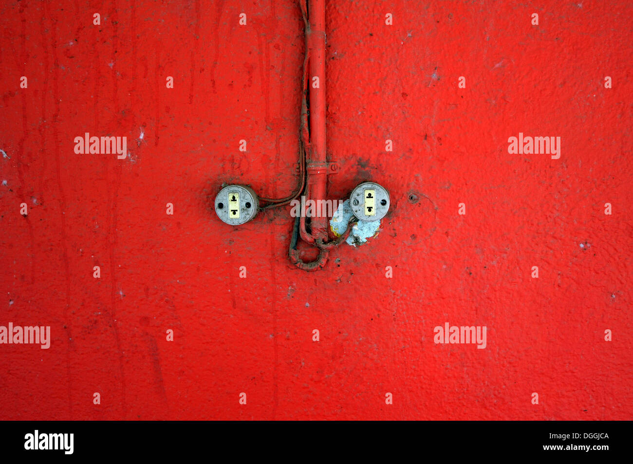 Schlampige Elektroinstallation auf einer roten Wand Stockfoto