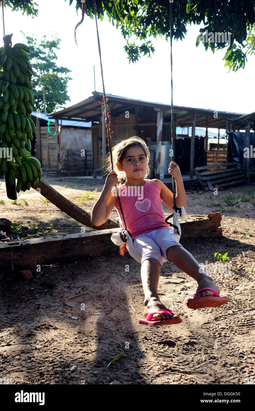 Mädchen, 6 schwingen auf einer Schaukel befestigt an einem Ast, San Gregorio, Caaguazu Abteilung, Paraguay Stockfoto