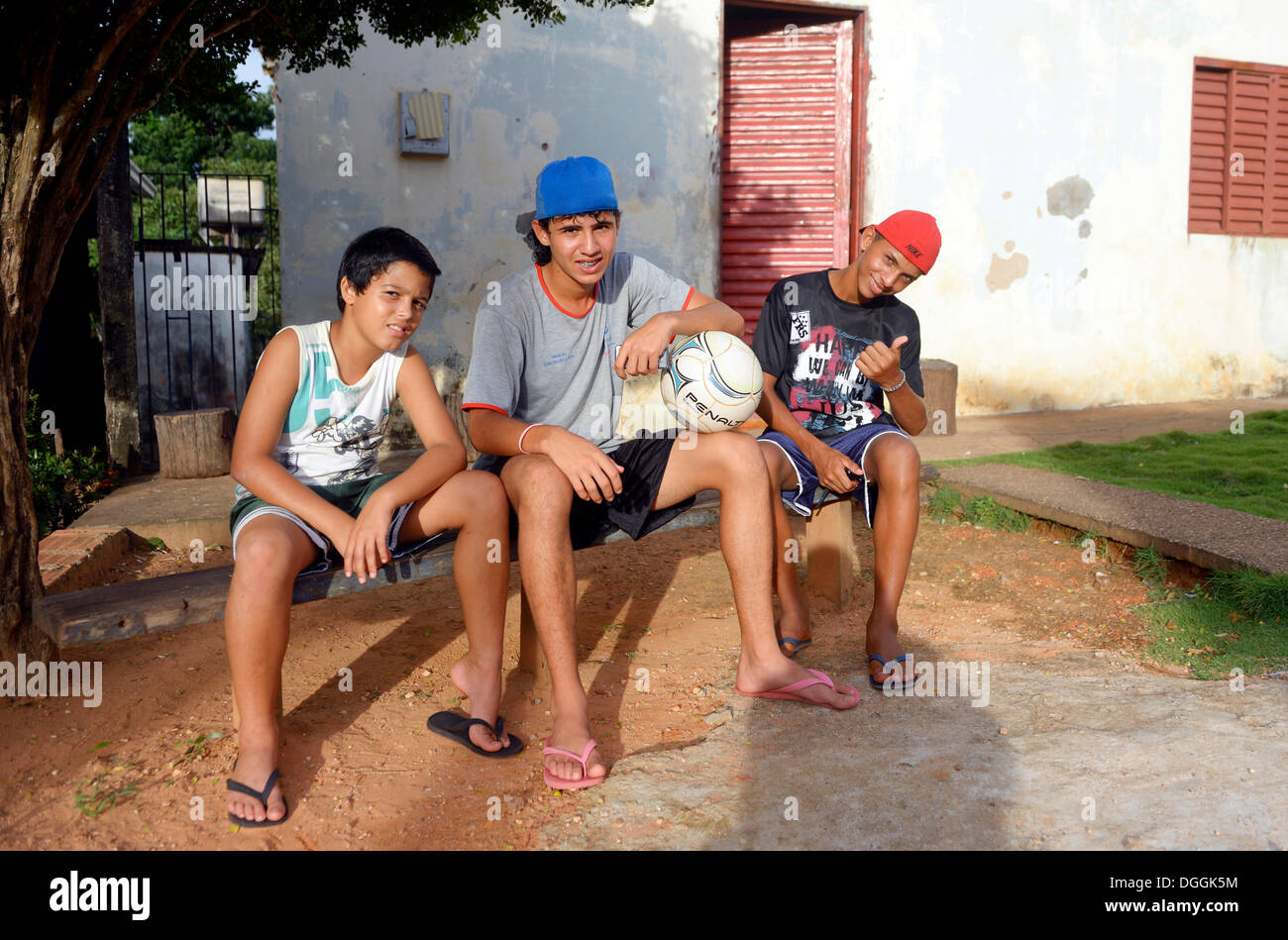 Junge Menschen mit einem Fußball sitzt vor ihrem Haus in einer Favela, Poxoréo, Mato Grosso, Brasilien Stockfoto
