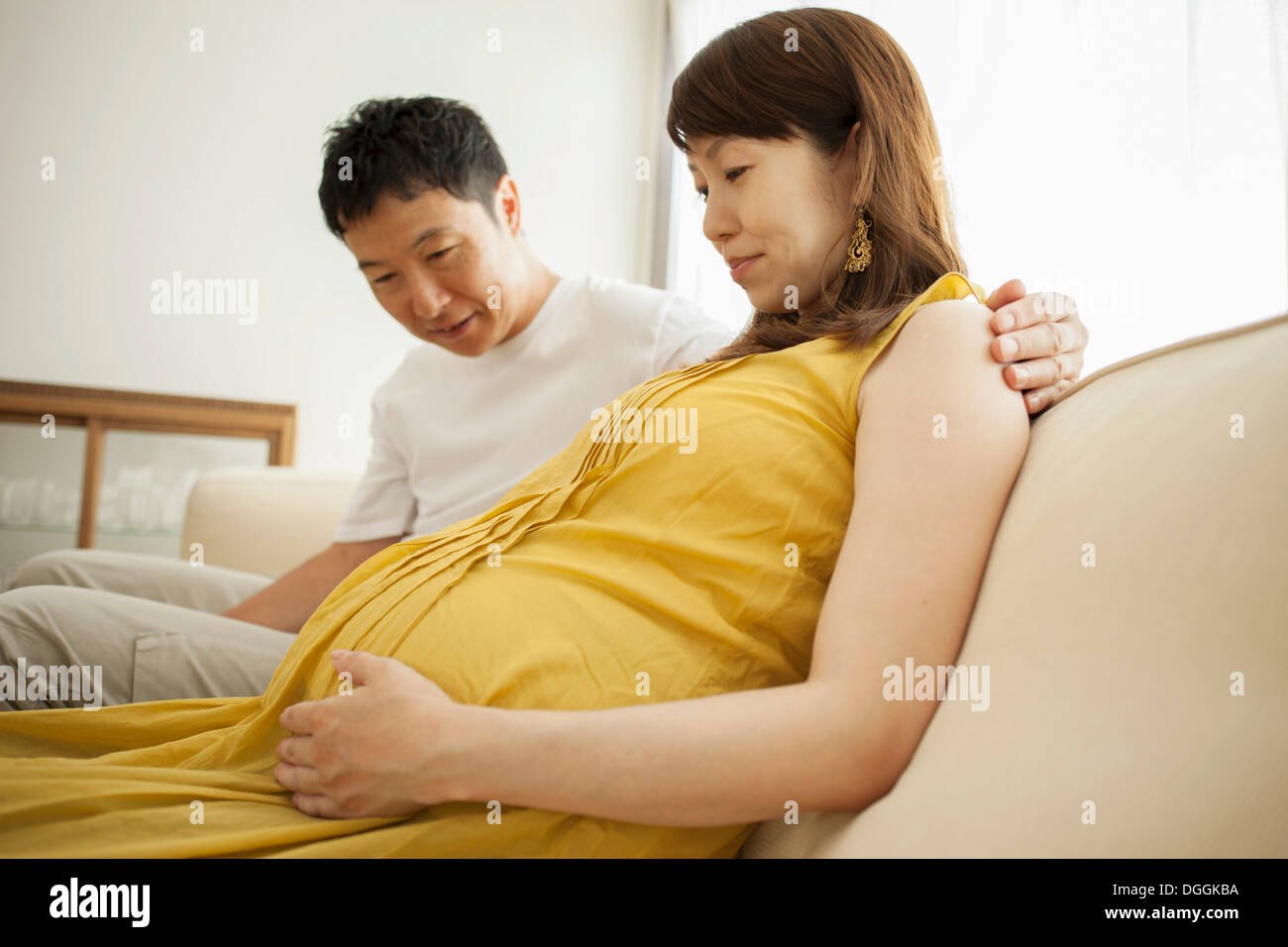 Mann am Bauch der schwangeren Frau auf sofa ...
