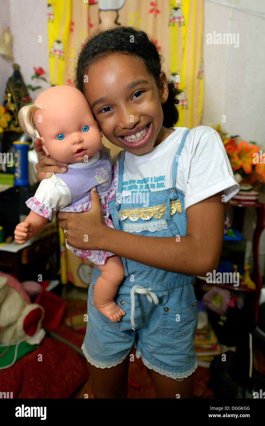 Mädchen, Lächeln, eine Puppe in einer Wohnung in einem Slum oder Favela, Jacarezinho Favela, Rio De Janeiro, Rio De Janeiro Zustand halten Stockfoto