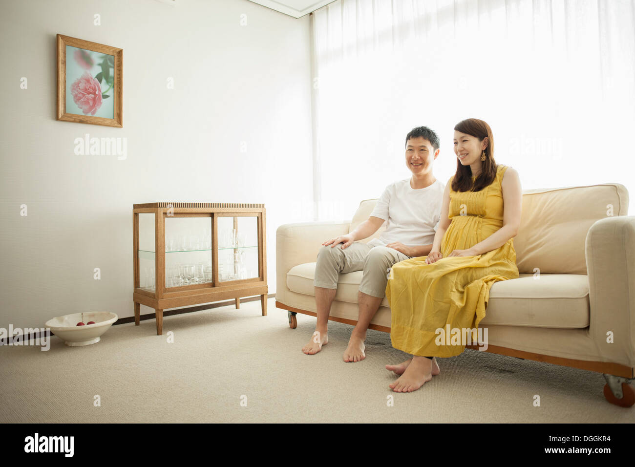 Mann und schwangere Frau sitzen auf sofa Stockfoto