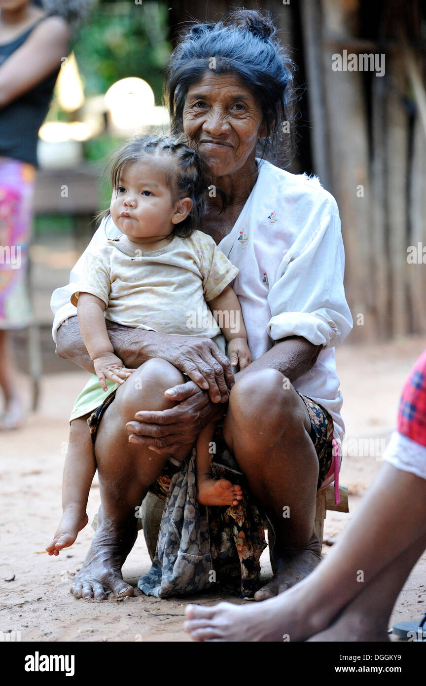 Ältere Frau mit einem Kind auf dem Schoß, in der Gemeinschaft der Mbya Guarani Indianer, Campito, Caaguazu Abteilung, Paraguay Stockfoto