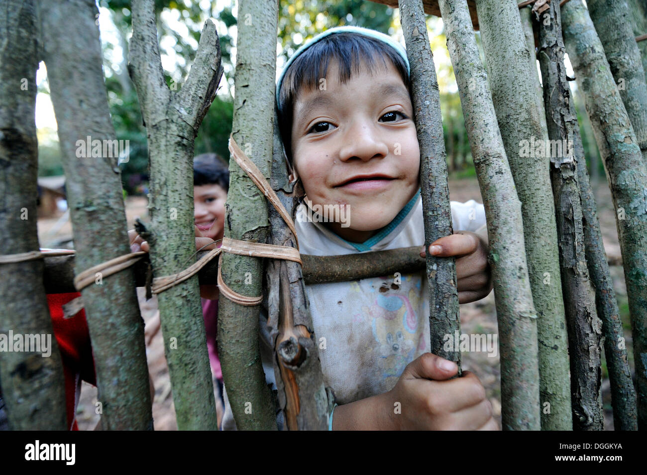 Freche junge, 6, Blick durch eine Lücke in einem Zaun in der Gemeinschaft der Mbya-Guarani-Indianer, Campito, Caaguazu Abteilung Stockfoto