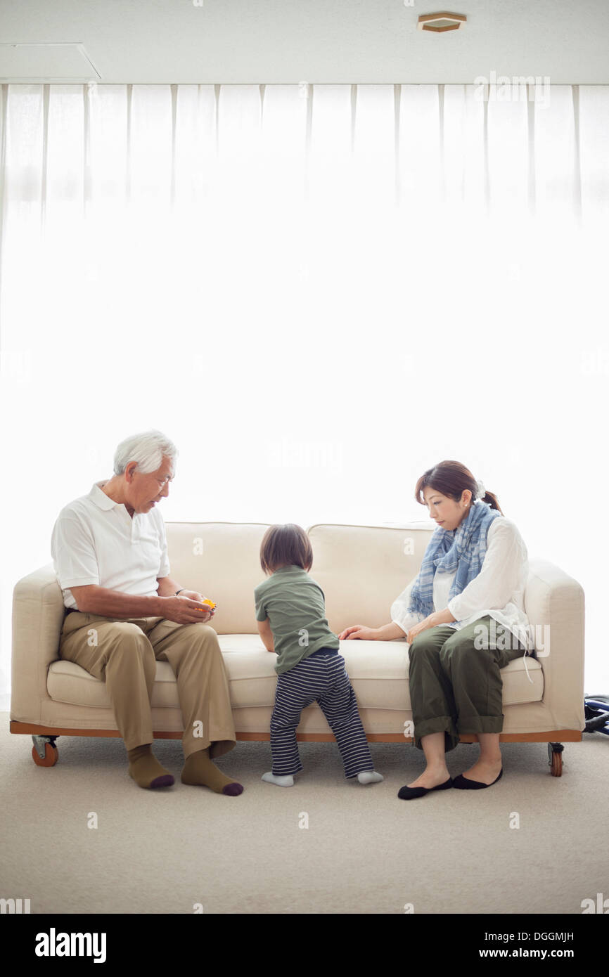 Junge mit seiner Mutter und Großvater auf sofa Stockfoto