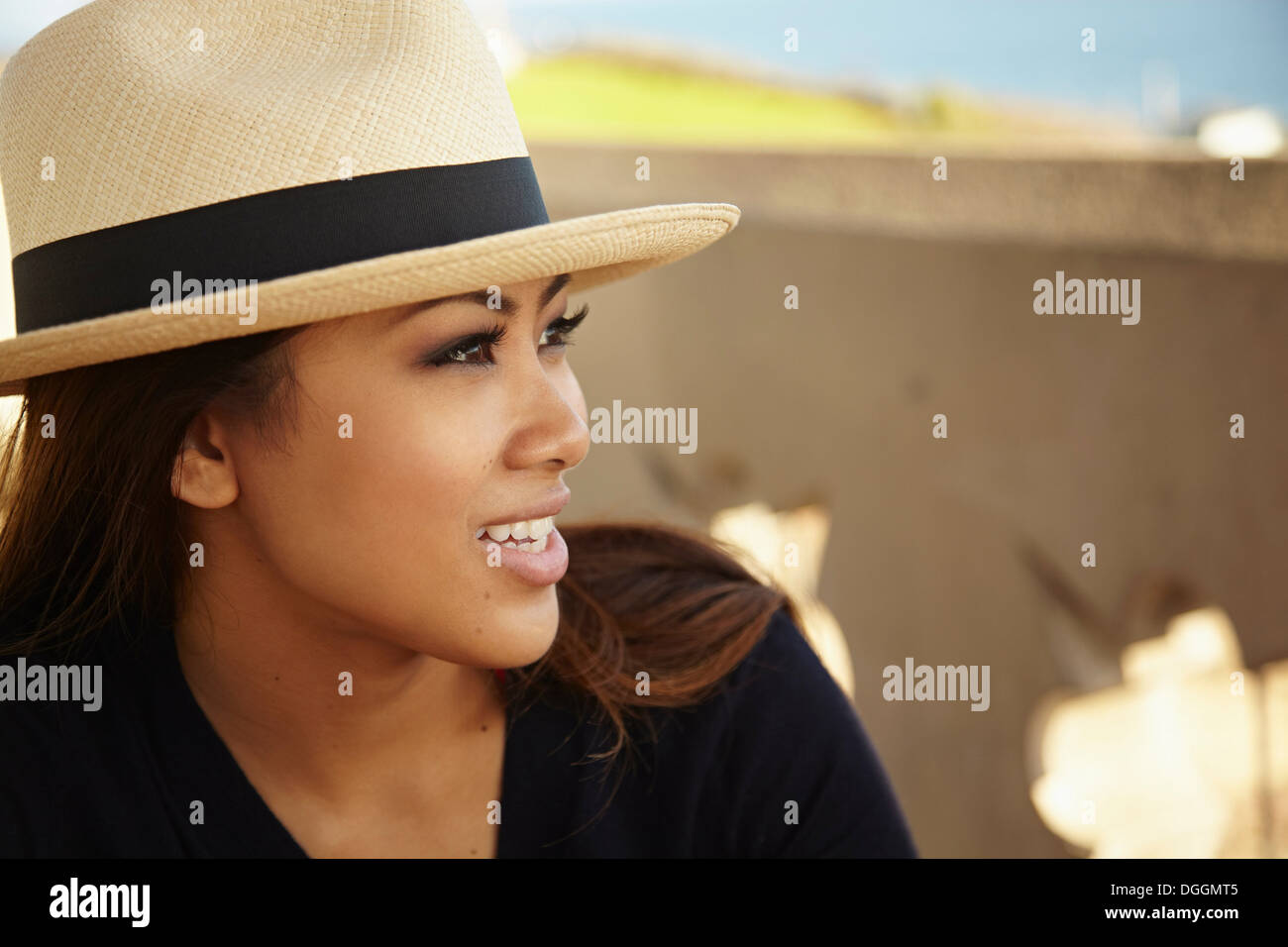 Porträt von lächelnden jungen Frau mit Sonnenhut an Küste Stockfoto