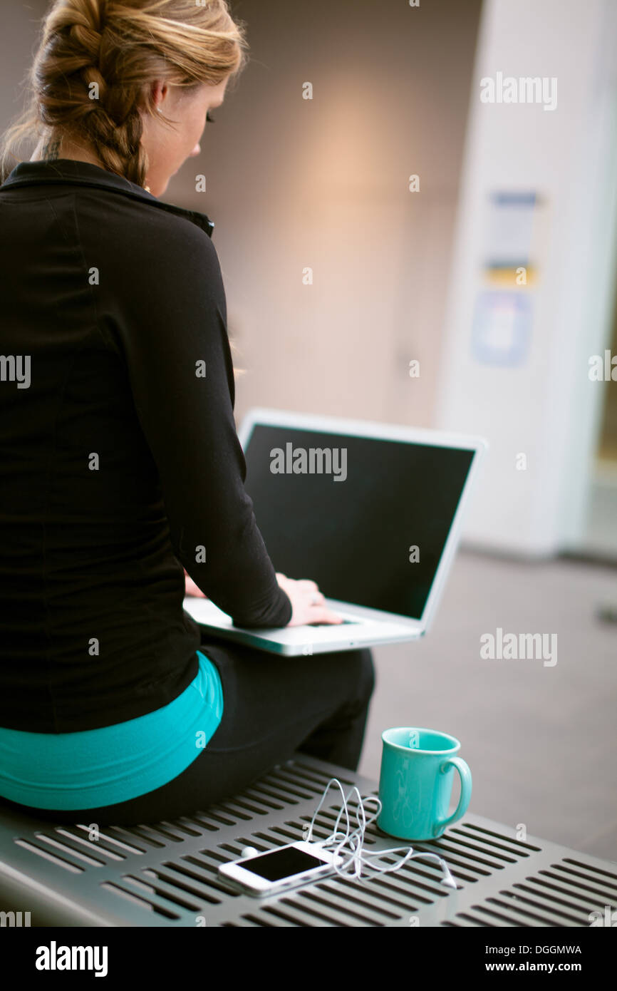 Junge Frau im Fitness-Studio-Korridor Blick auf laptop Stockfoto