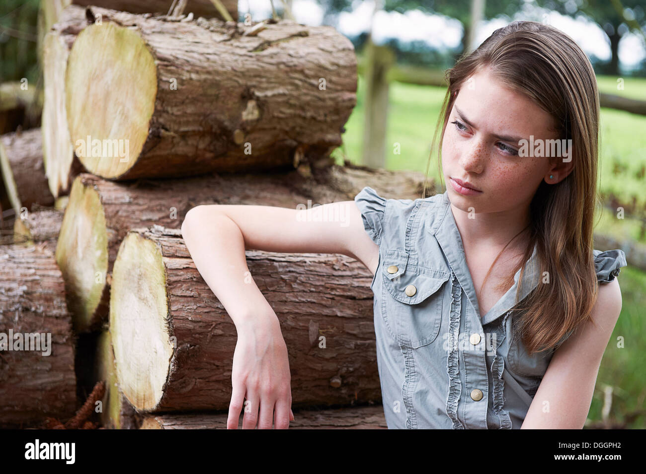 Teenager-Mädchen stützte sich auf Protokolle im Wald Stockfoto