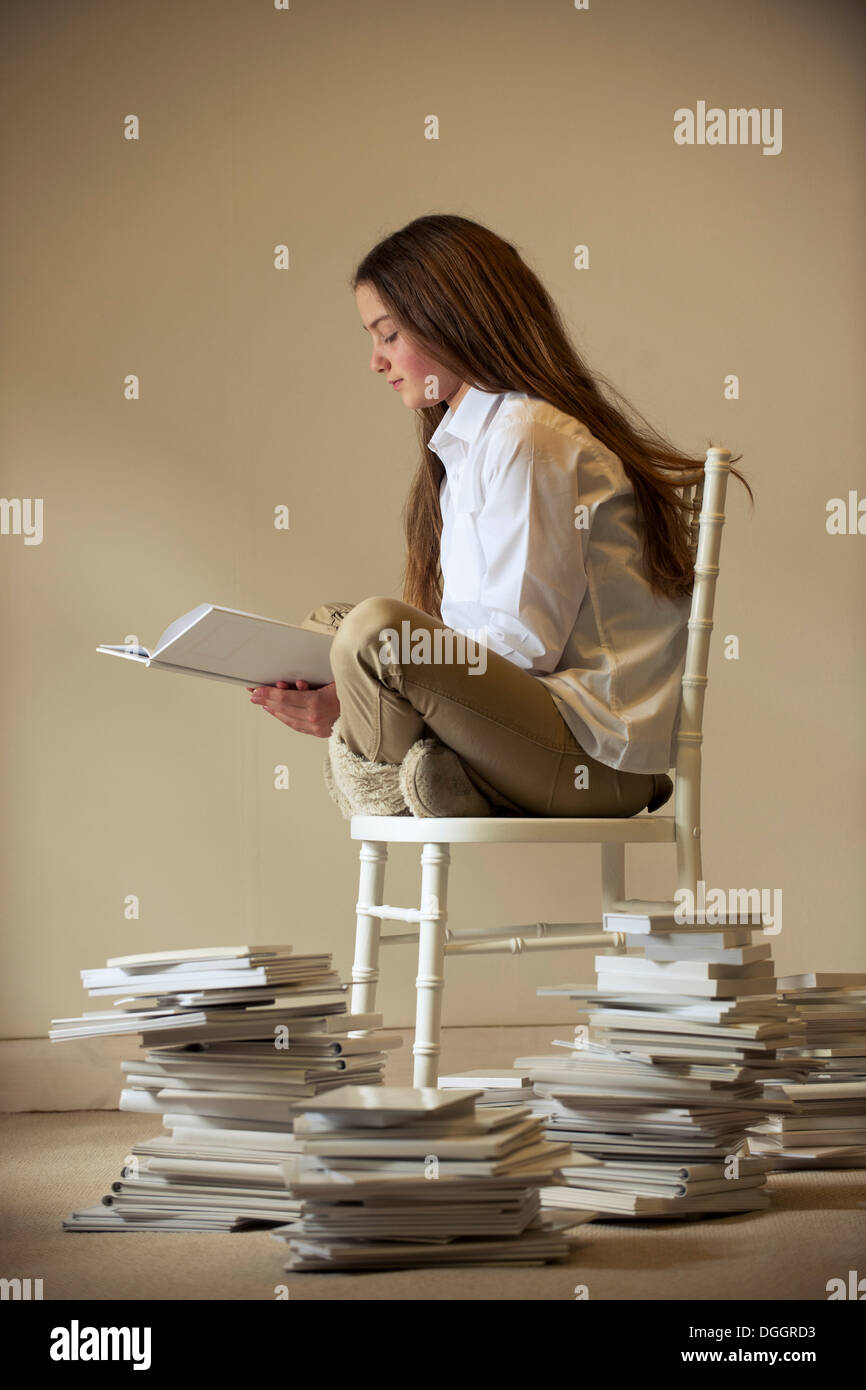 Mädchen sitzen auf Stuhl Buch Stockfoto
