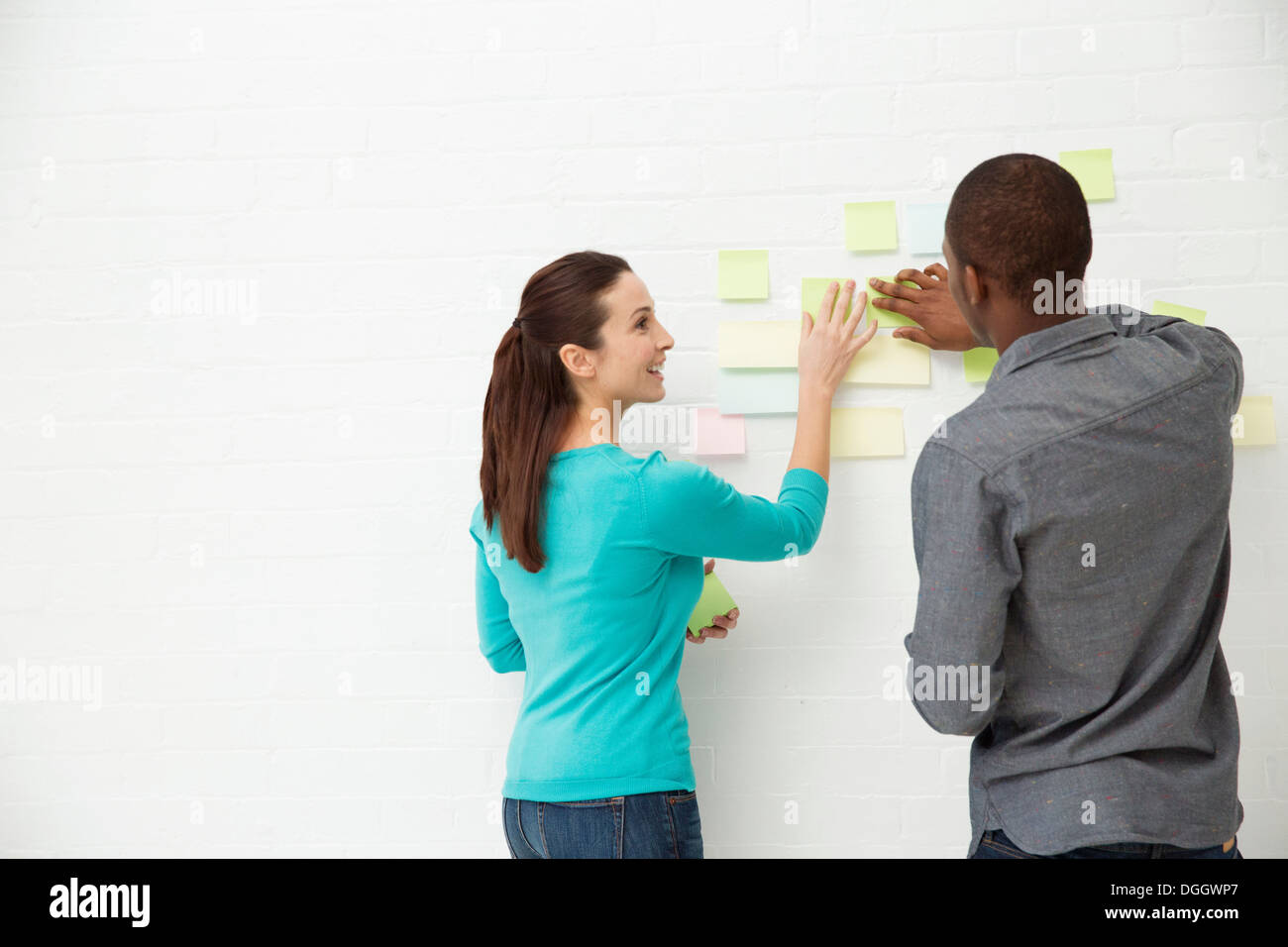 Zwei Kollegen kleben Klebefuge Notizen an der Wand Stockfoto