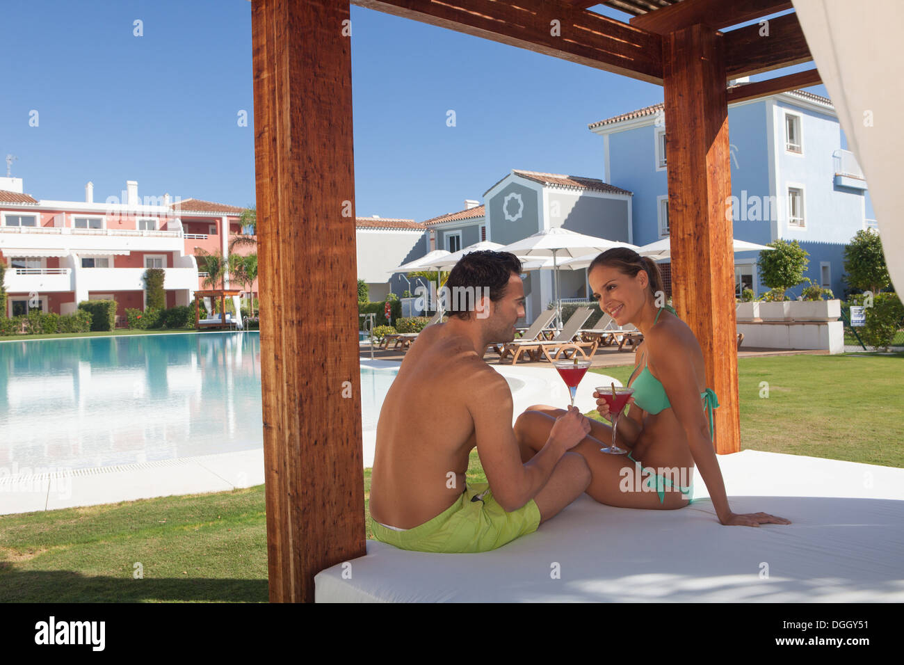 Junges Paar sitzt auf der Sonnenliege im Holiday Resort mit cocktails Stockfoto