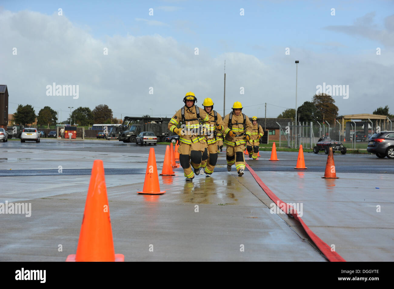 Mildenhall Teammitglieder, gekleidet in Feuerwehrmann schützende Ausrüstung, konkurrieren in der dritten jährlichen Feuer aufbringen 10. Oktober 2013, auf RAF Mildenhall, England. Gerade beendet das Team die sechsten Veranstaltung, ein trockener Schlauch voraus, in dem sie einen Feuerwehrschlauch ziehen ein paar Hu musste Stockfoto