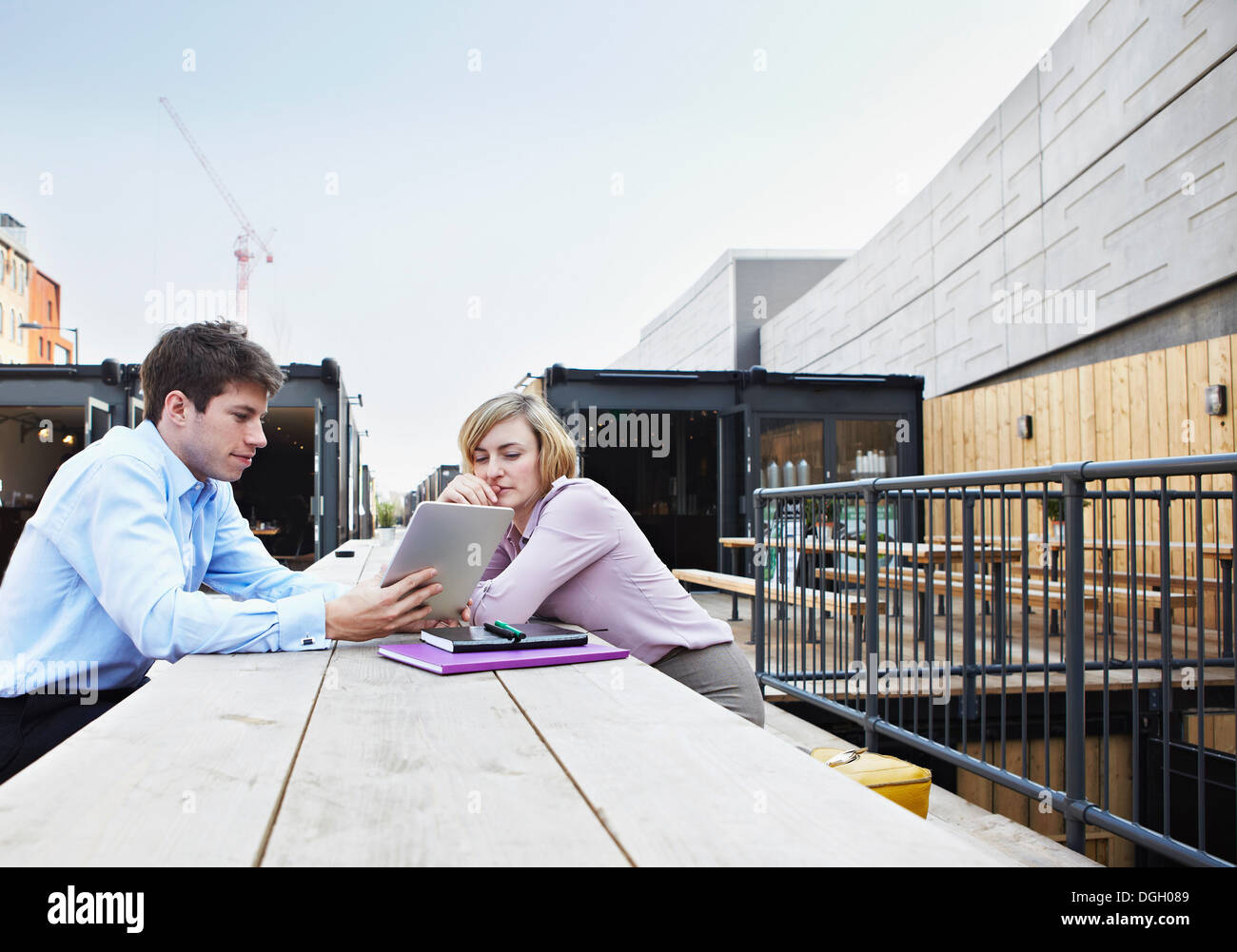 Zwei Leute sitzen am Tisch mit digitalen Tablet im freien Stockfoto