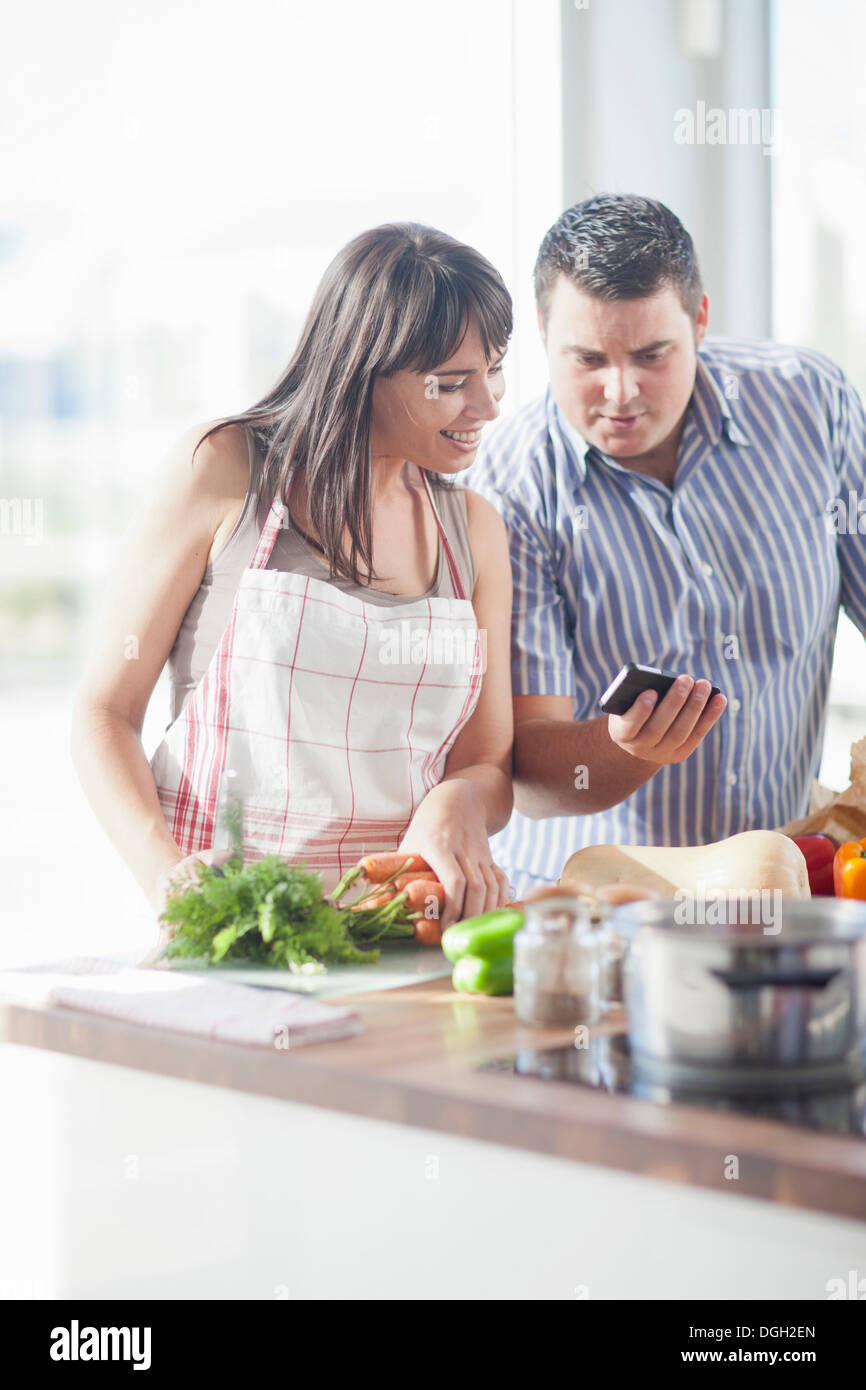 Paar auf der Suche auf Smartphone, während die Zubereitung von Speisen Stockfoto