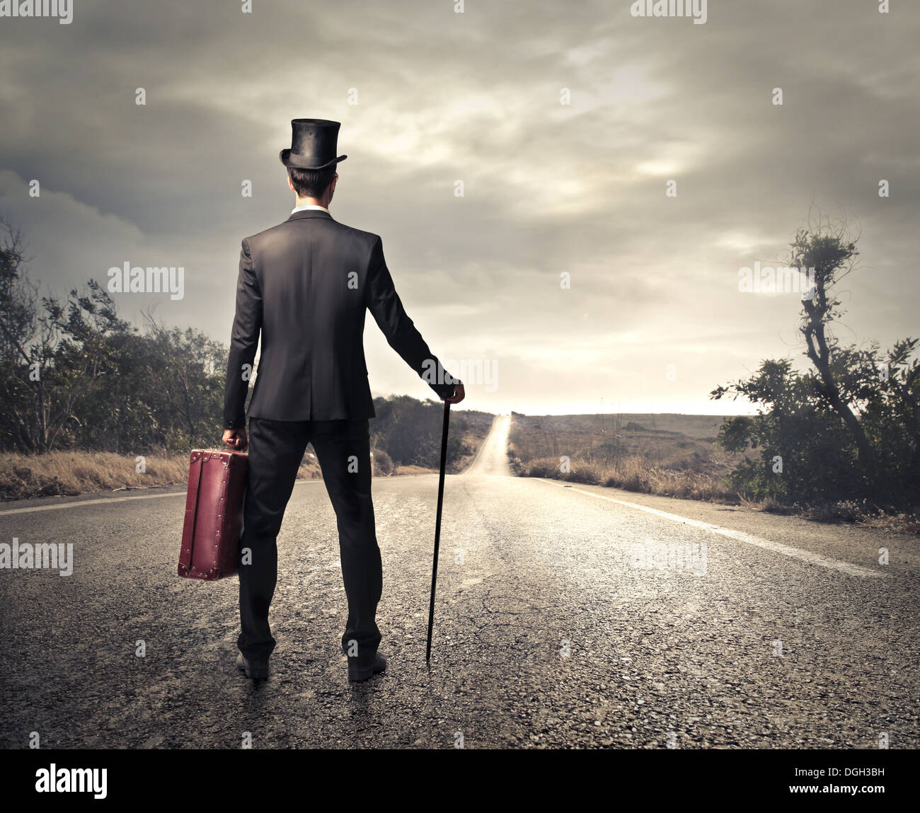 Mann stehend mit einer Aktentasche und einem Stick auf einer Autobahn Stockfoto