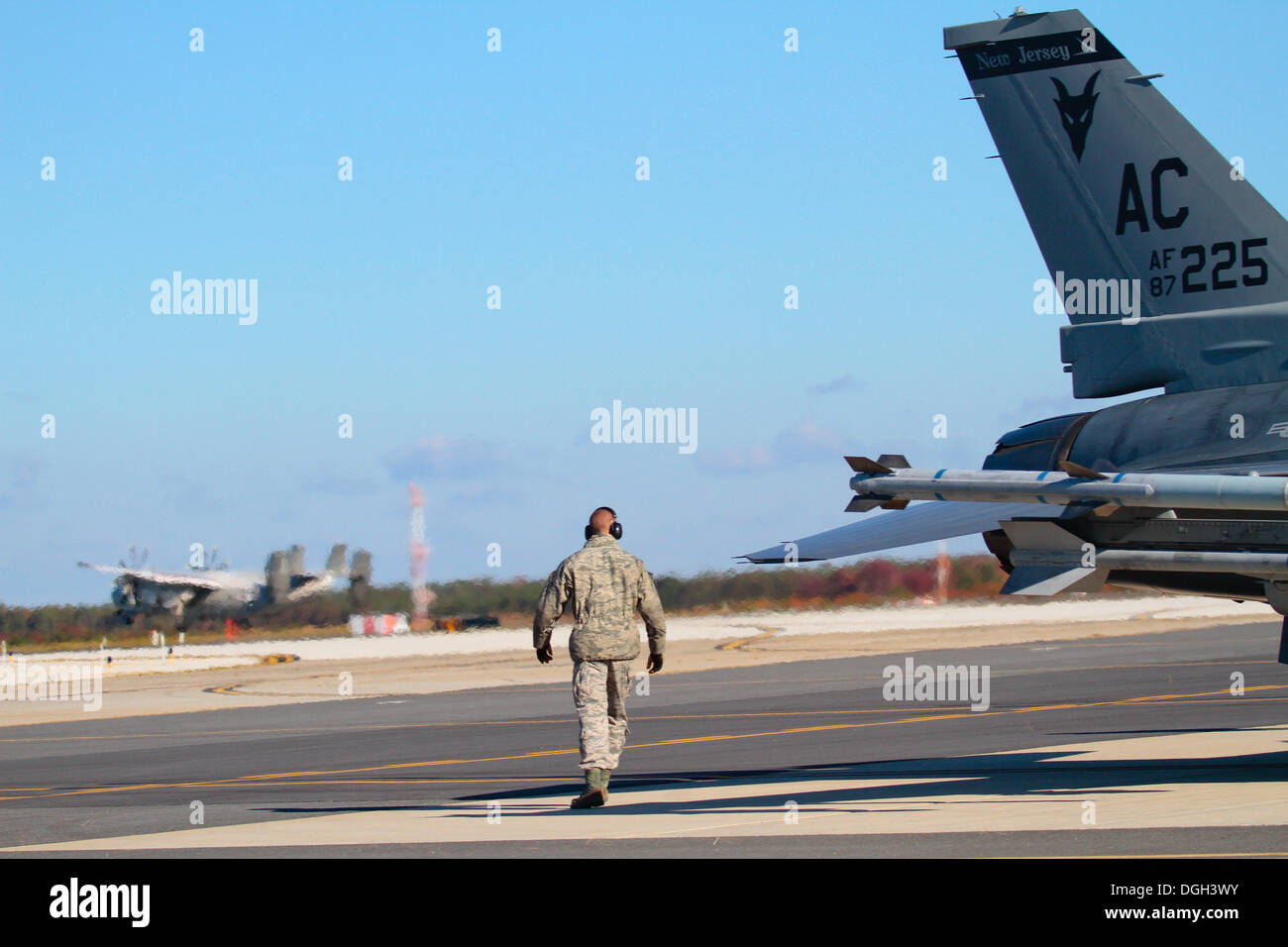 U.S. Air Force Airman First Class Alex Petrella hat einige Last-Minute-Prüfungen auf ein F - 16C Fighting Falcon von der New Jersey Air National Guard 177. Kämpfer-Flügel, wie eine US-Marine C-2A Greyhound von VAW-120 im Hintergrund am 18. Oktober im Atlantic landet Stockfoto