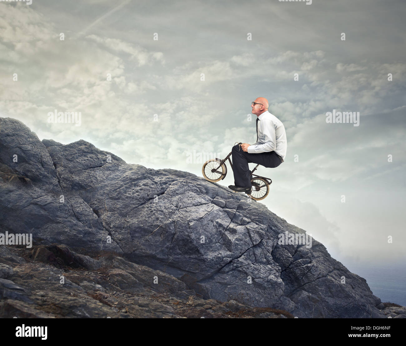 Glatze Büroangestellte einen felsigen Berg mit einem kleinen Motorrad Stockfoto