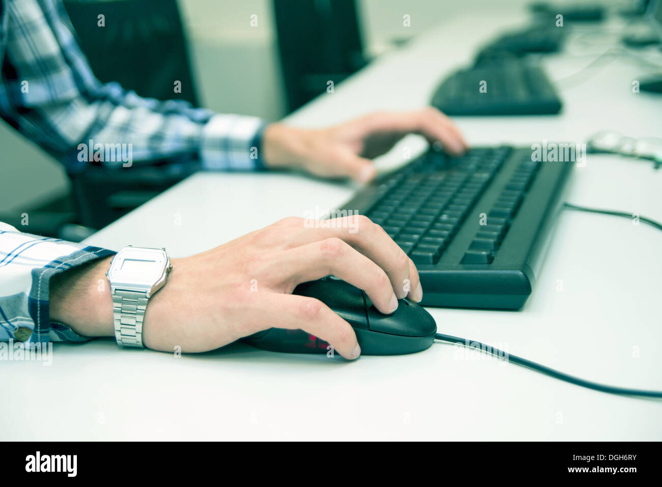 Junger Mann über Tastatur eingeben. Schulungsraum mit Computern Stockfoto