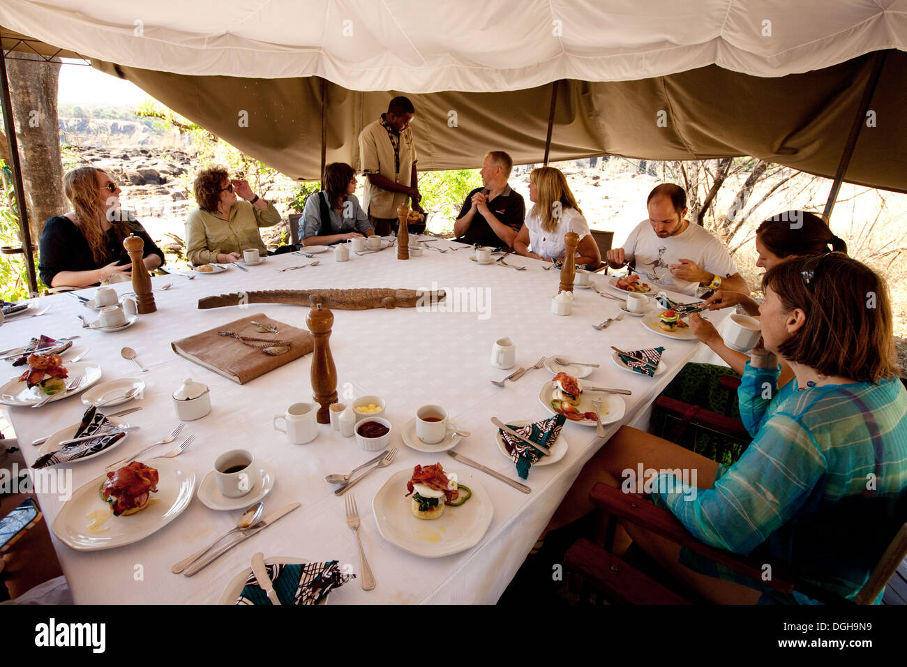 Touristen, die mit einem Safari-Frühstück in einem Zelt am Livingstone Island in der Nähe von Victoria Falls, Sambia Afrika Stockfoto