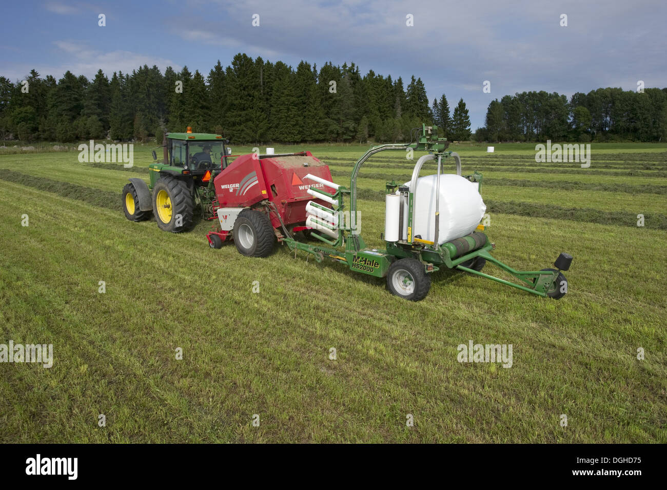 Silage Ernte, John Deere 4455 Traktor mit Rundballenpresse und Ballenwickler, Pressen und wickeln von Rundballen, Schweden, august Stockfoto
