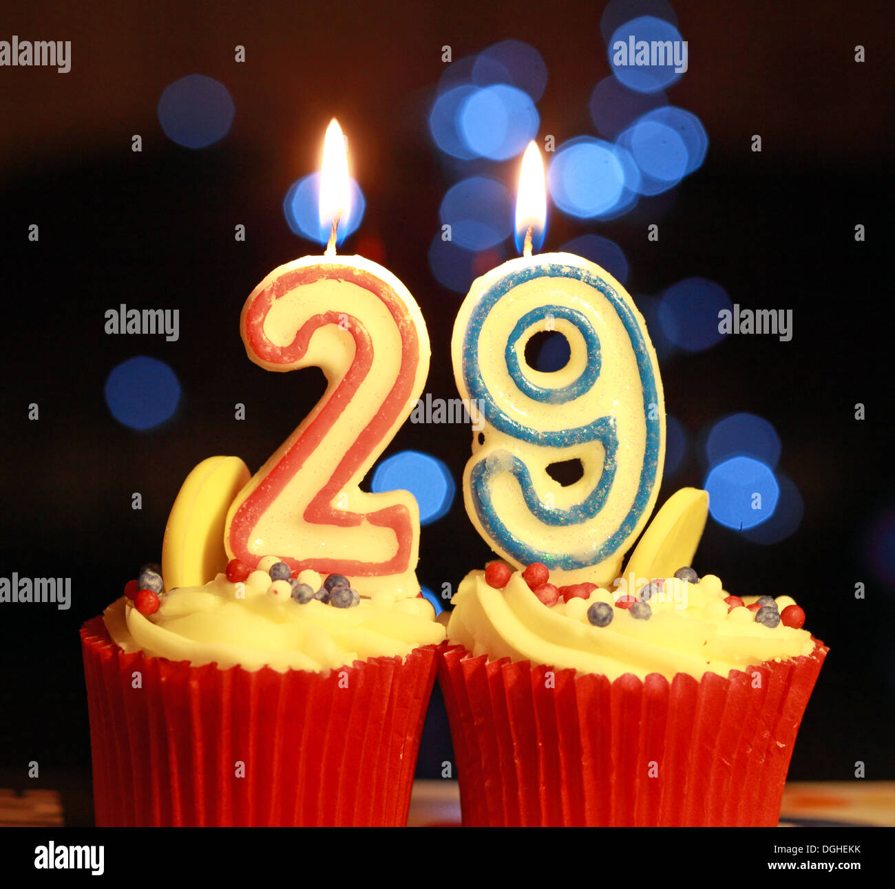Twentynine die Nummer 29 als brennende Kerzen, auf vereisten Muffins, 29. Geburtstag, mit Bokeh Stockfoto