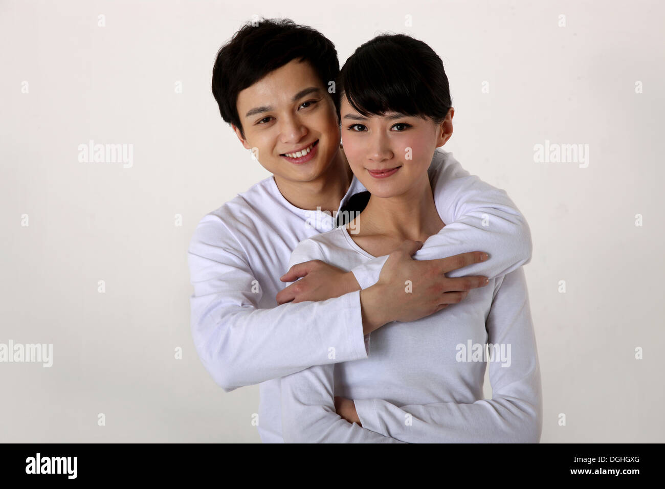 Ostasiatische paar umarmt, lächelnd, in die Kamera schaut Stockfoto
