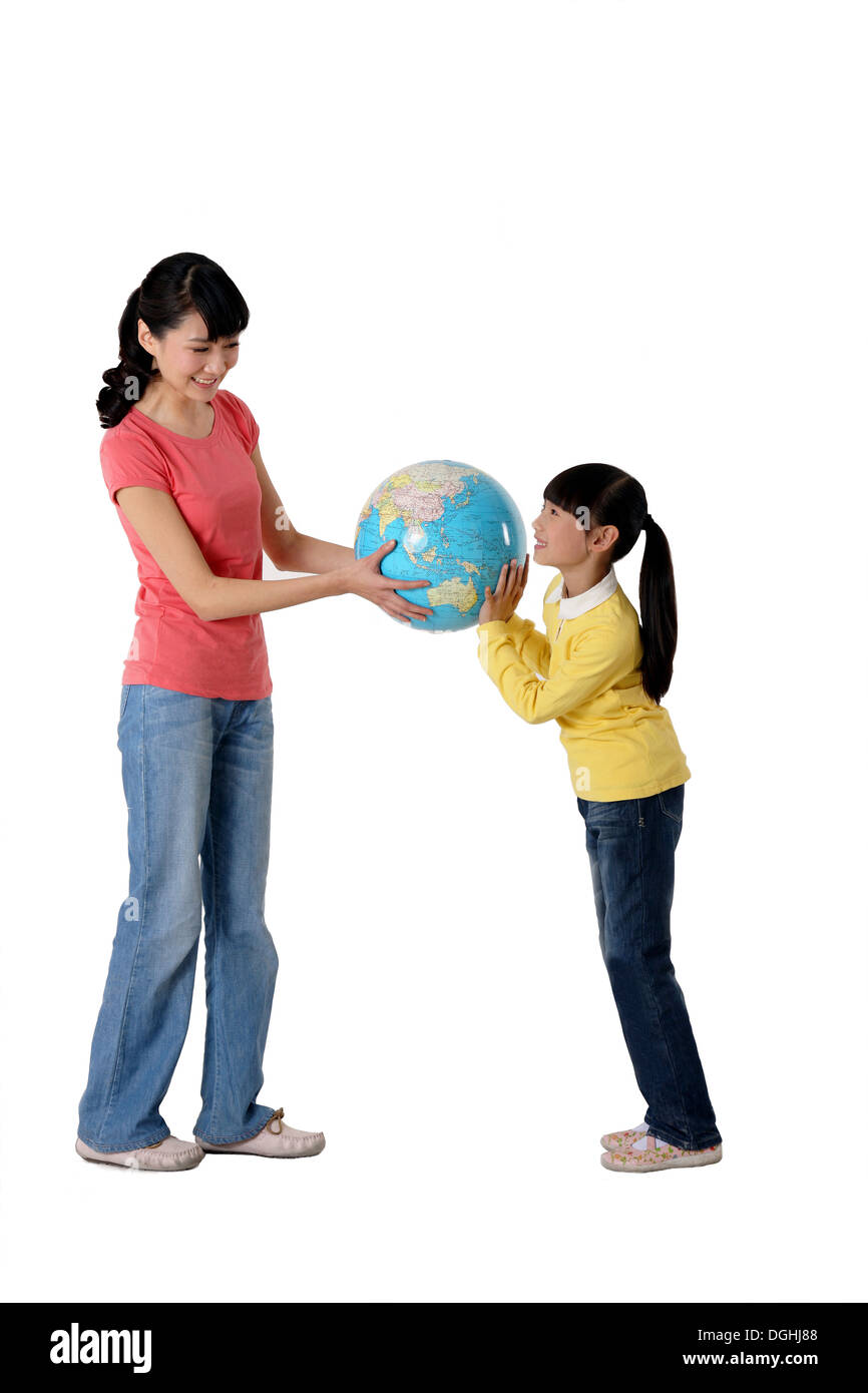 East Asian Mutter und Tochter halten Globus, auf dem Boden stehend Stockfoto