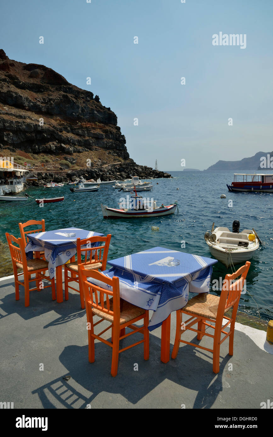 Tische und Stühle im Restaurant "Katína" im Ammoúdi Hafen von Oia, Santorini, Cyclades, griechische Inseln, Griechenland Stockfoto