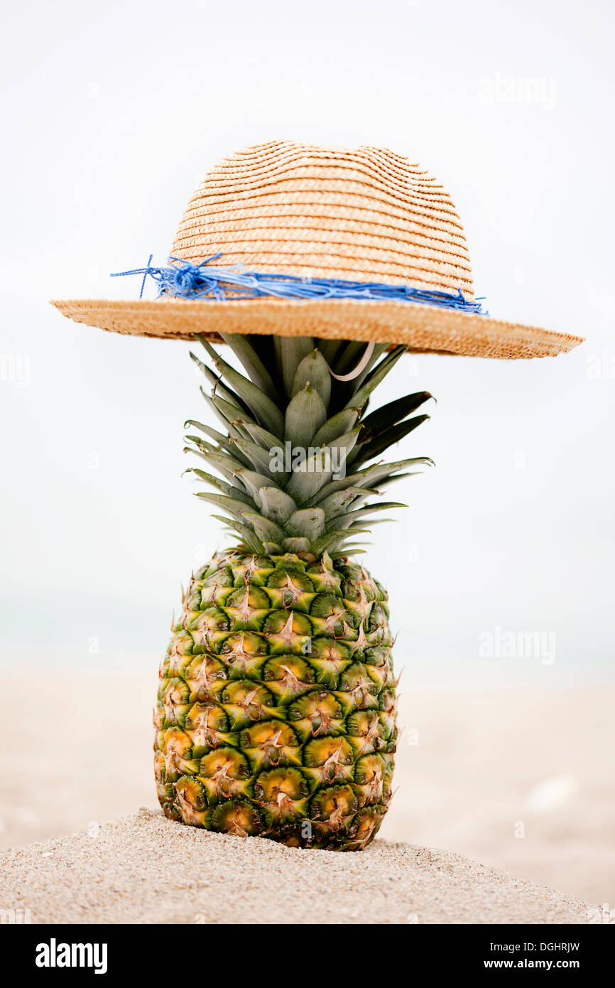 eine Ananas mit einem Hut am Strand Stockfoto