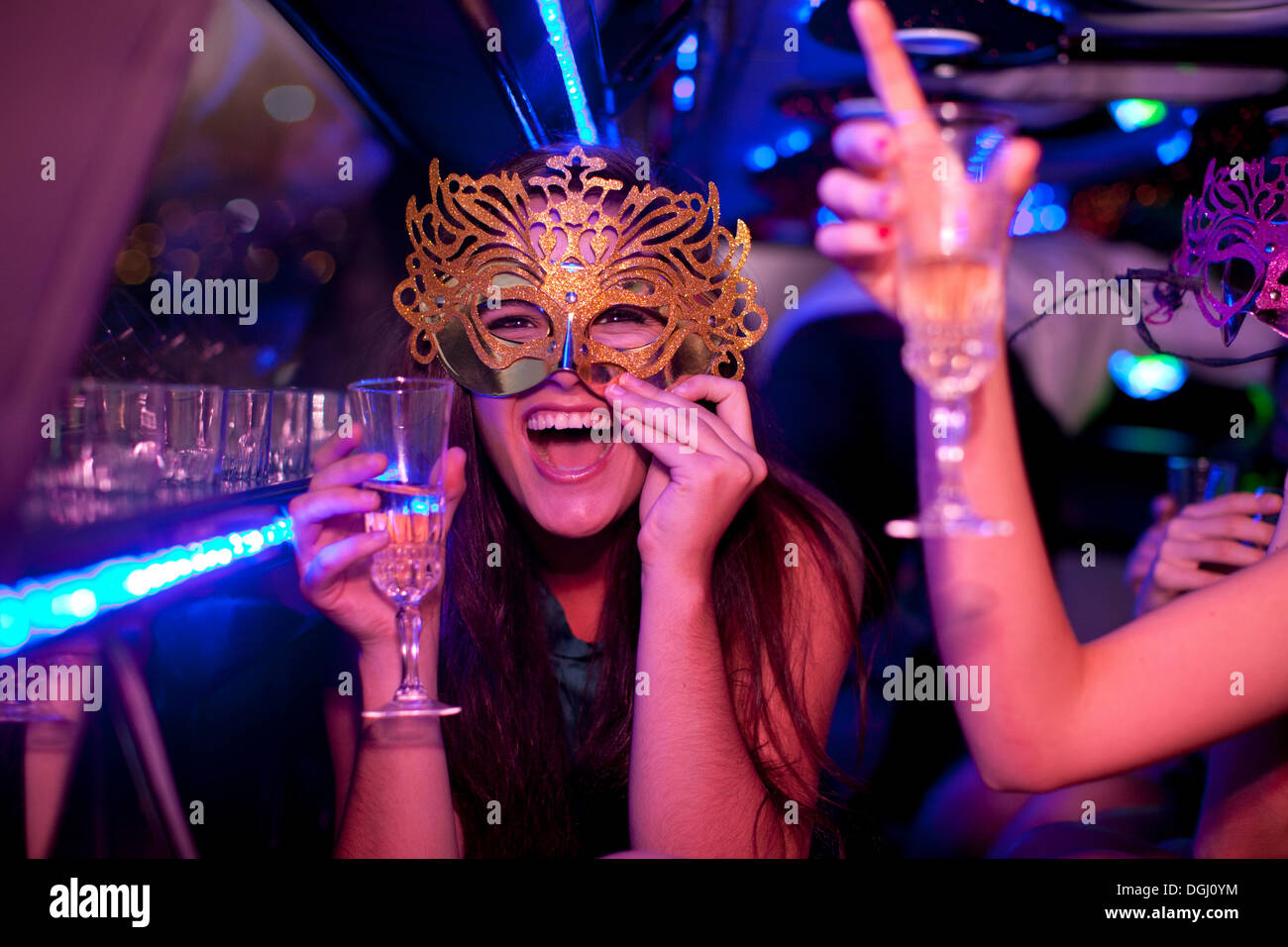 Junge Frau mit Maske mit Weinglas in limousine Stockfoto