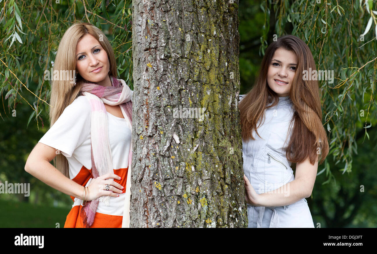 Zwei junge Frauen neben einem Baumstamm Stockfoto