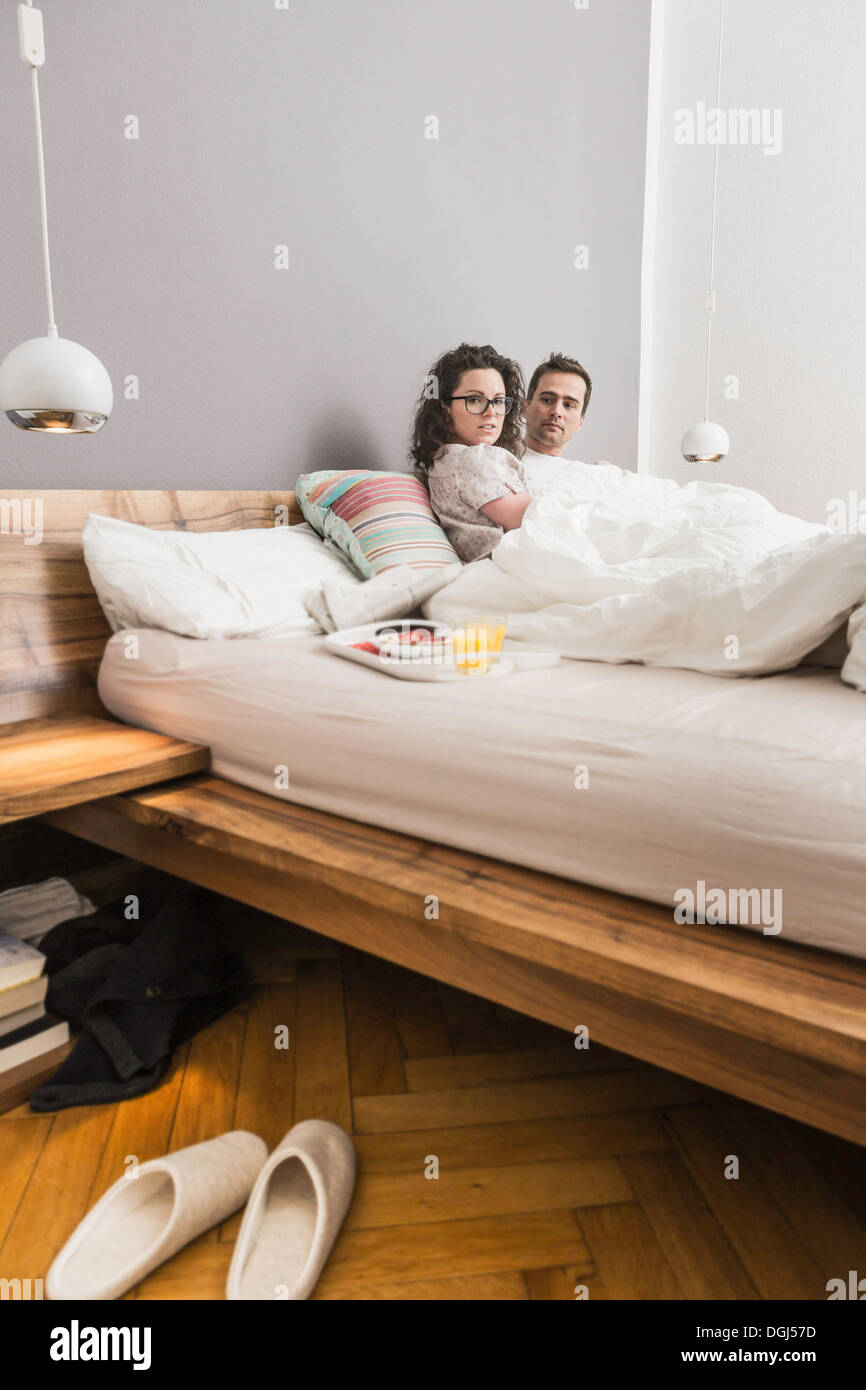 Mitte erwachsenes paar im Bett liegend Frühstück auf Tablett Stockfoto