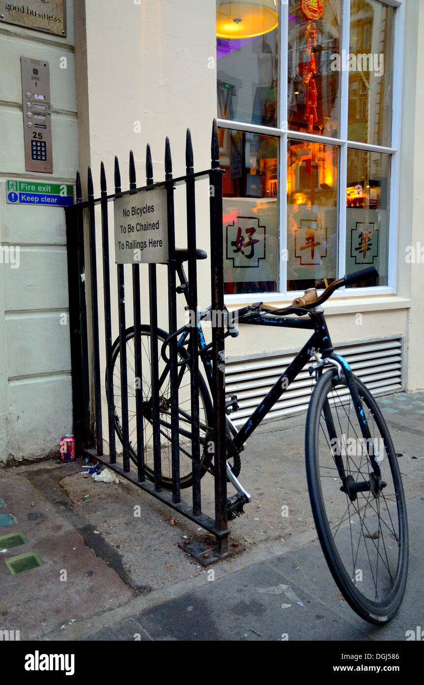 Fahrrad angekettet an Geländer unten ein "keine Fahrräder auf Geländer hier verkettet werden" Zeichen. Gerrard St, London. Stockfoto
