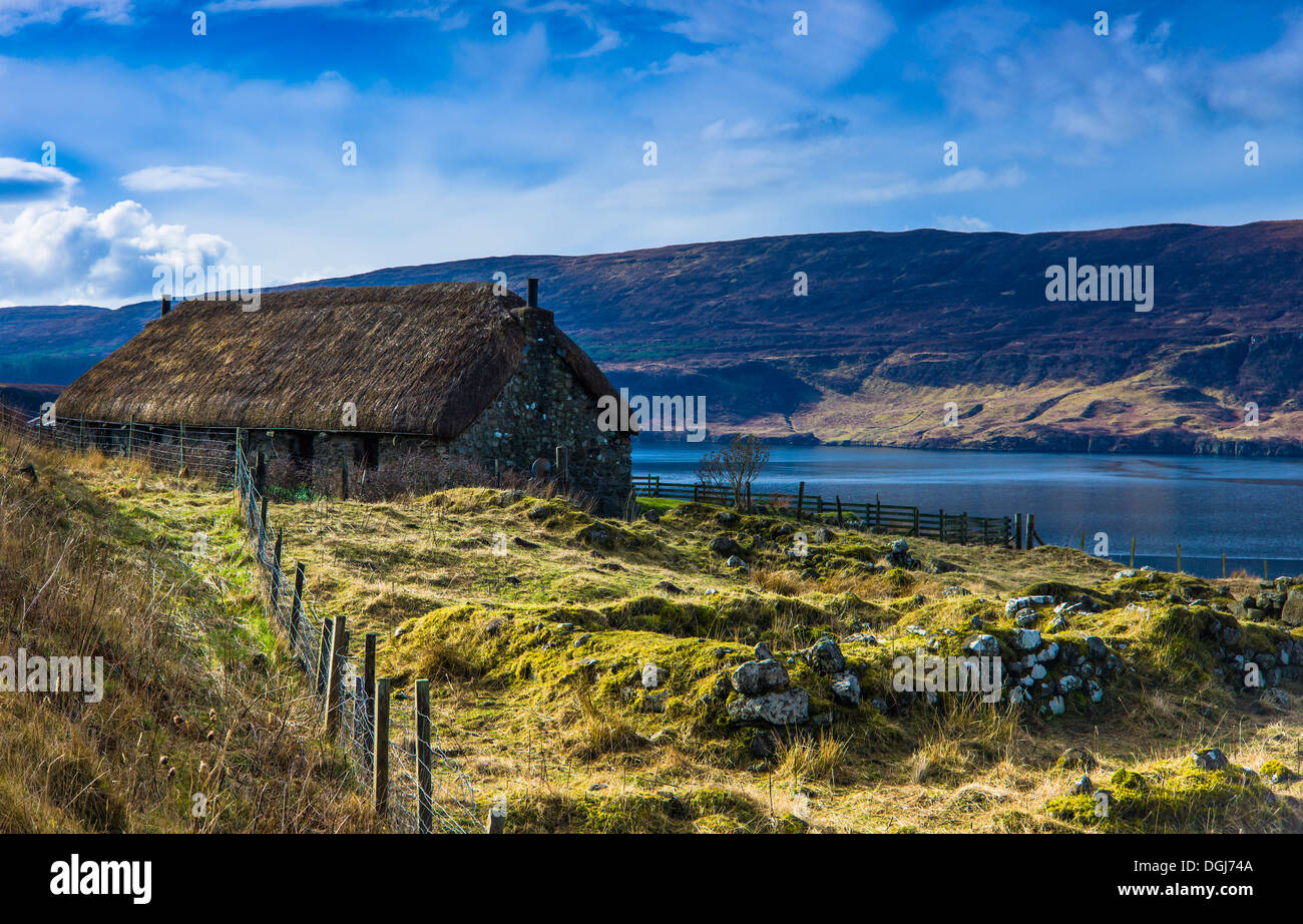 Eine traditionelle Blackhouse in der Nähe von Uig auf der Isle Of Skye mit Ruinen der alten Gebäude im Vordergrund. Stockfoto
