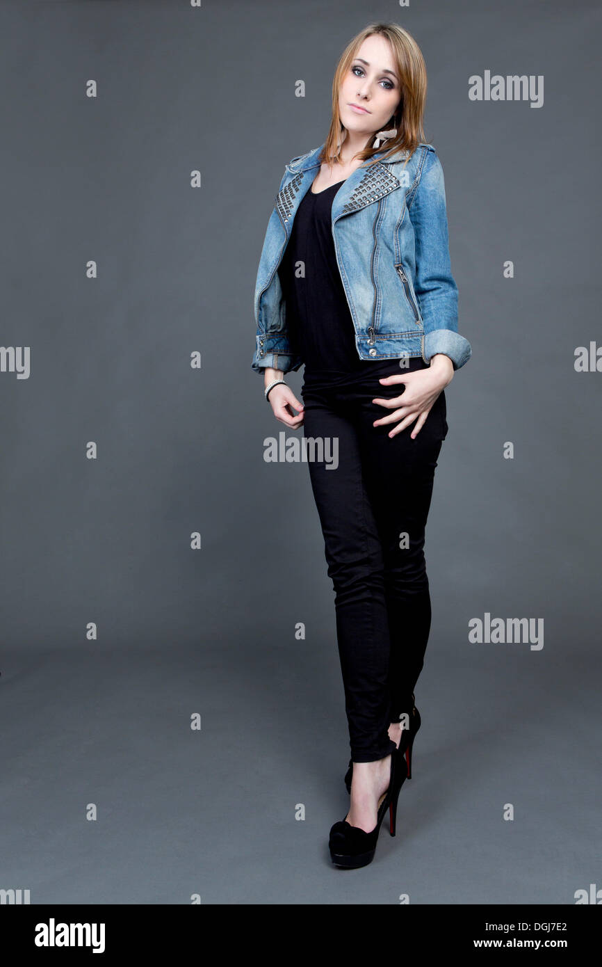 Junge Frau trägt eine Jeansjacke, schwarze Hose und high heels Stockfoto