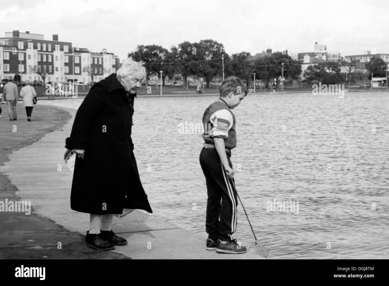 ältere Dame wacht über junge Angeln für Krebse bei Kanu See Southsea uk in den 1990er Jahren Stockfoto
