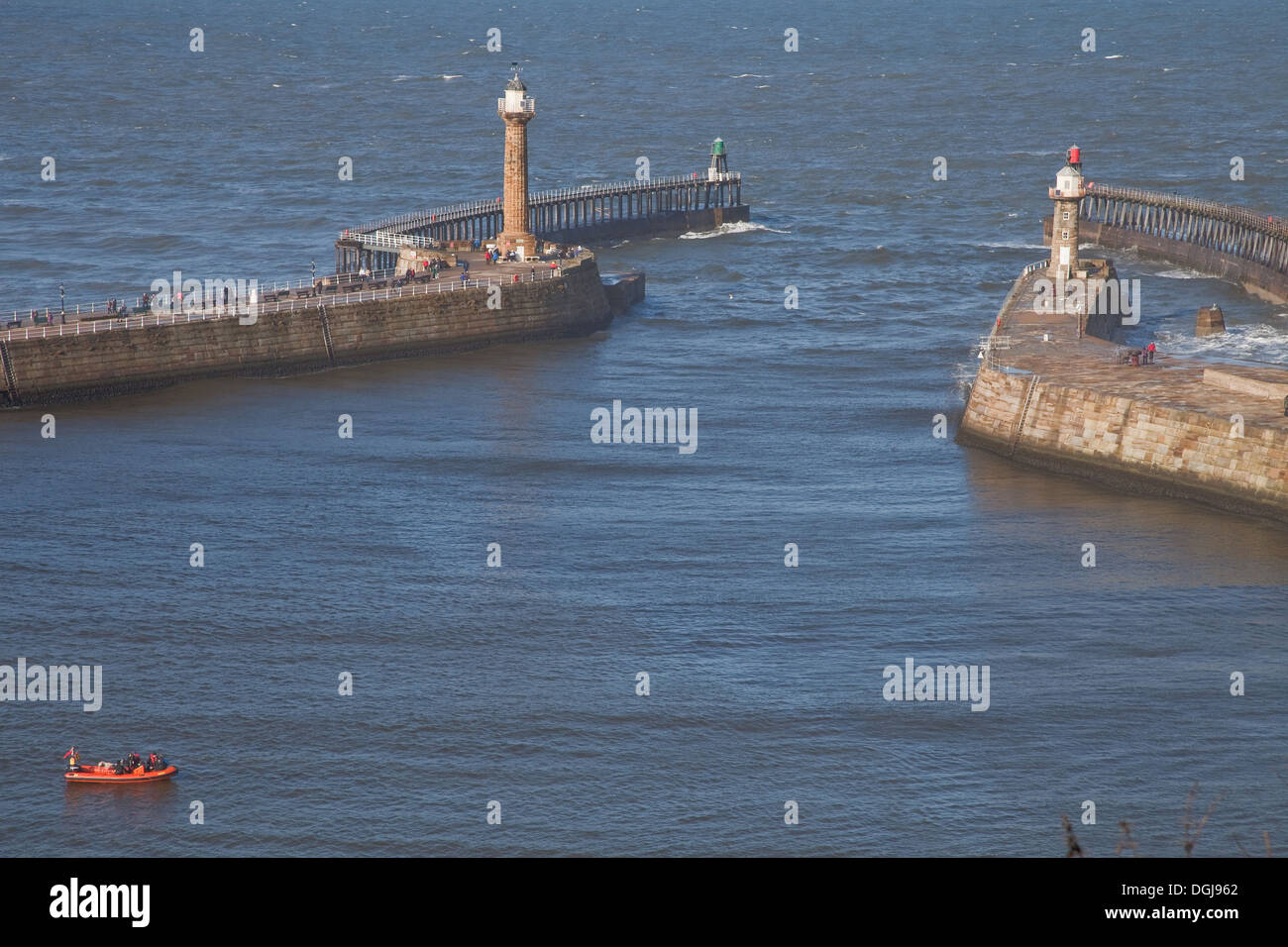 Eingang zum Hafen von Whitby und Deich.   Kleine orange Schlauchboot mit Tauchern, die Vorbereitung, über die Seite zu gehen. Stockfoto