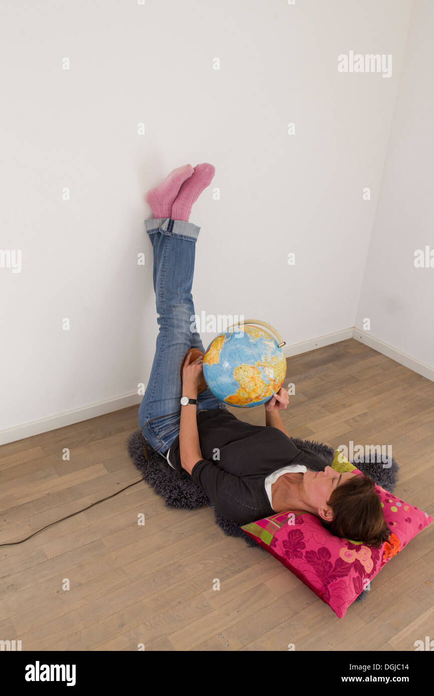 Frau liegt auf dem Boden der leeren Raum halten Globus Stockfoto