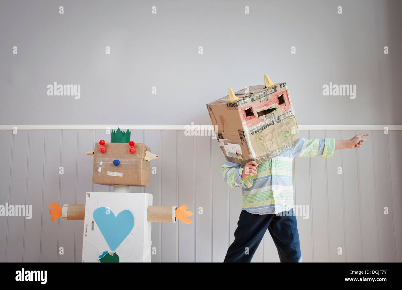 Junge mit Box für Kopf und hausgemachte Spielzeugroboter Stockfoto