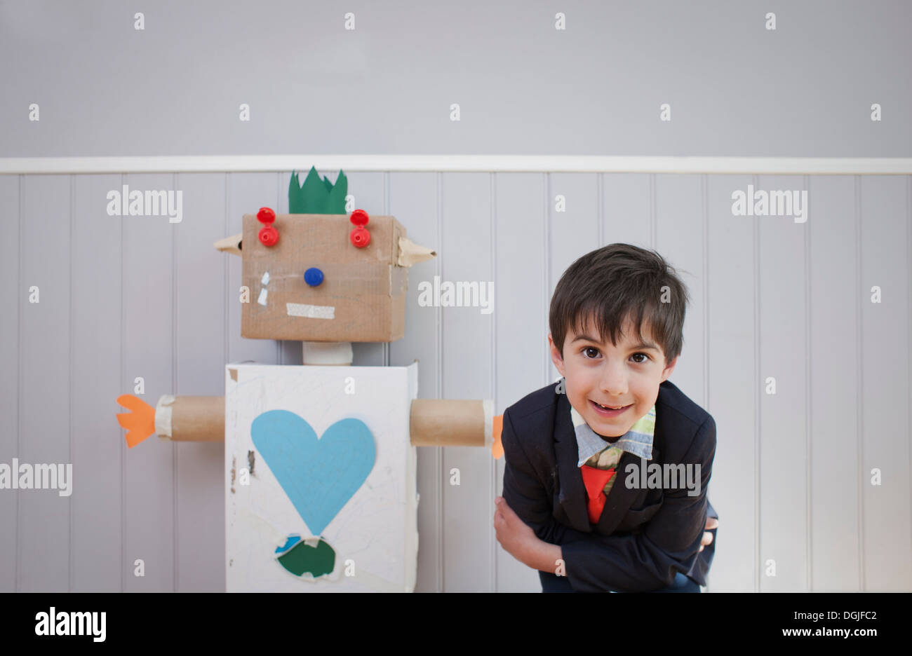 Junge, die Neigung zu Kamera mit hausgemachten Spielzeugroboter Stockfoto