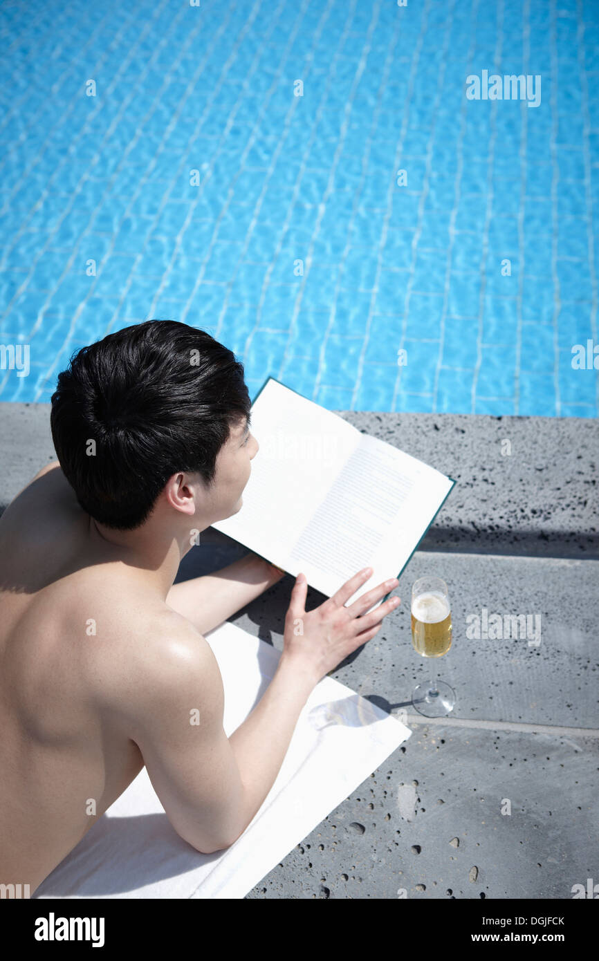 ein Mann liest ein Buch am pool Stockfoto