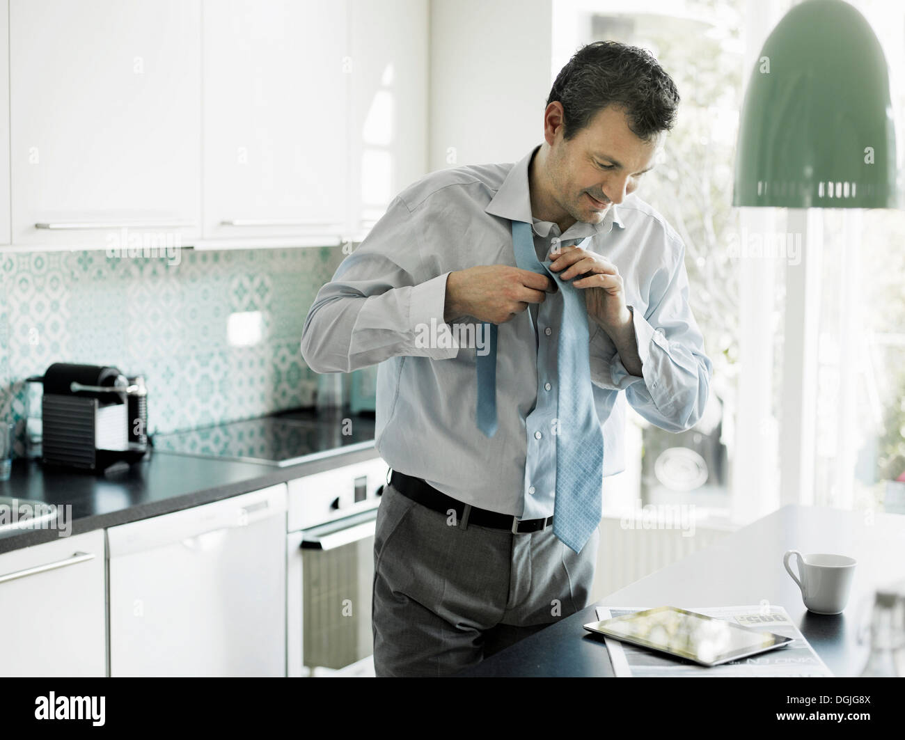 Reife Geschäftsmann immer bereit und mit Tablette in der Küche Stockfoto