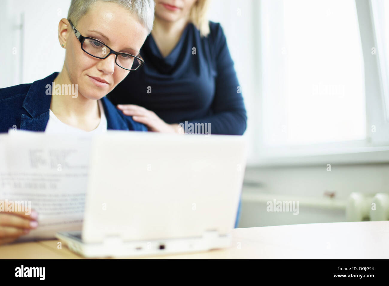 Geschäftsfrau mit Papierkram mit Kollegen Hand auf Schulter Stockfoto