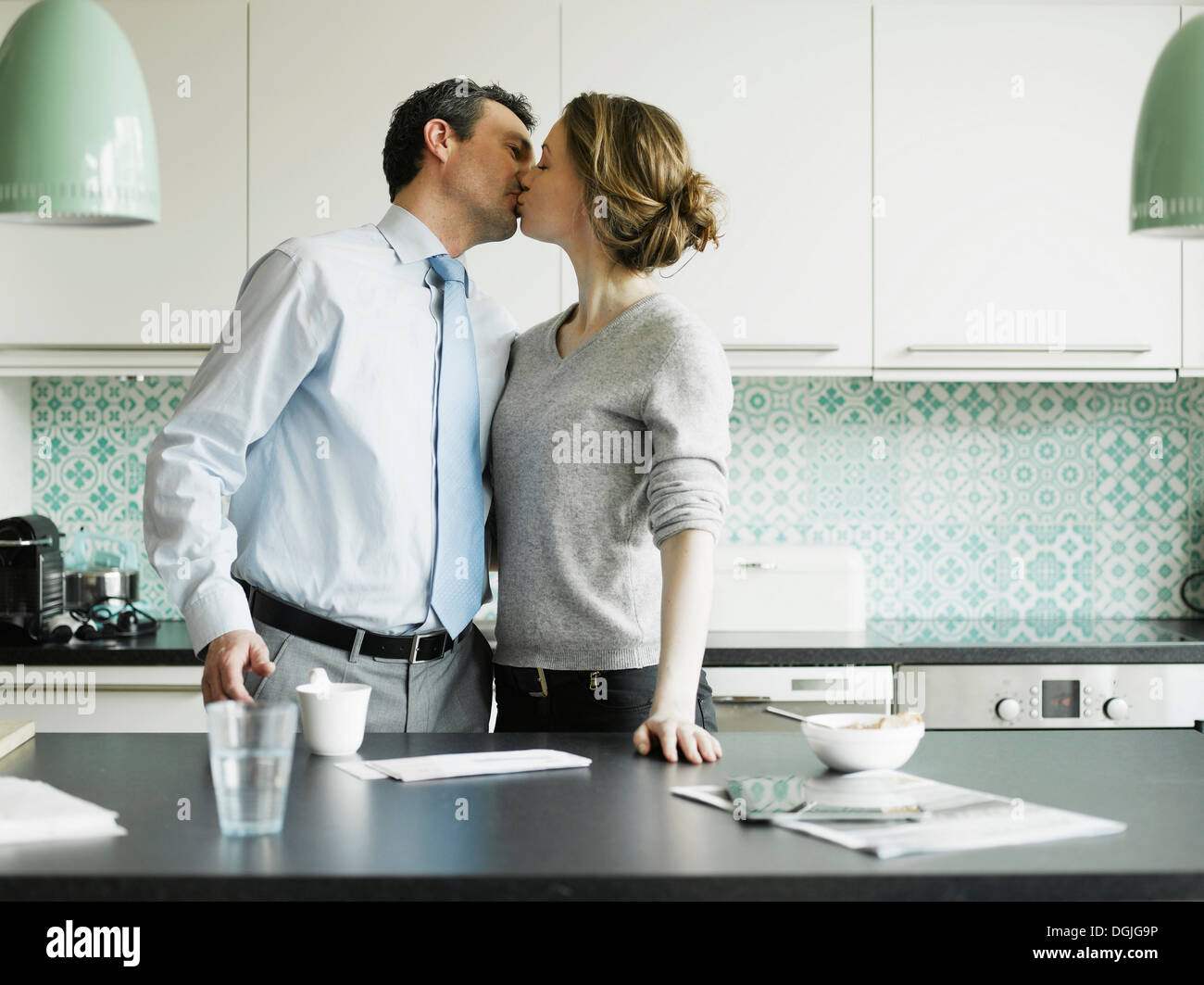 Mitte Erwachsene Frau küssen Geschäftsmann in Küche Stockfoto
