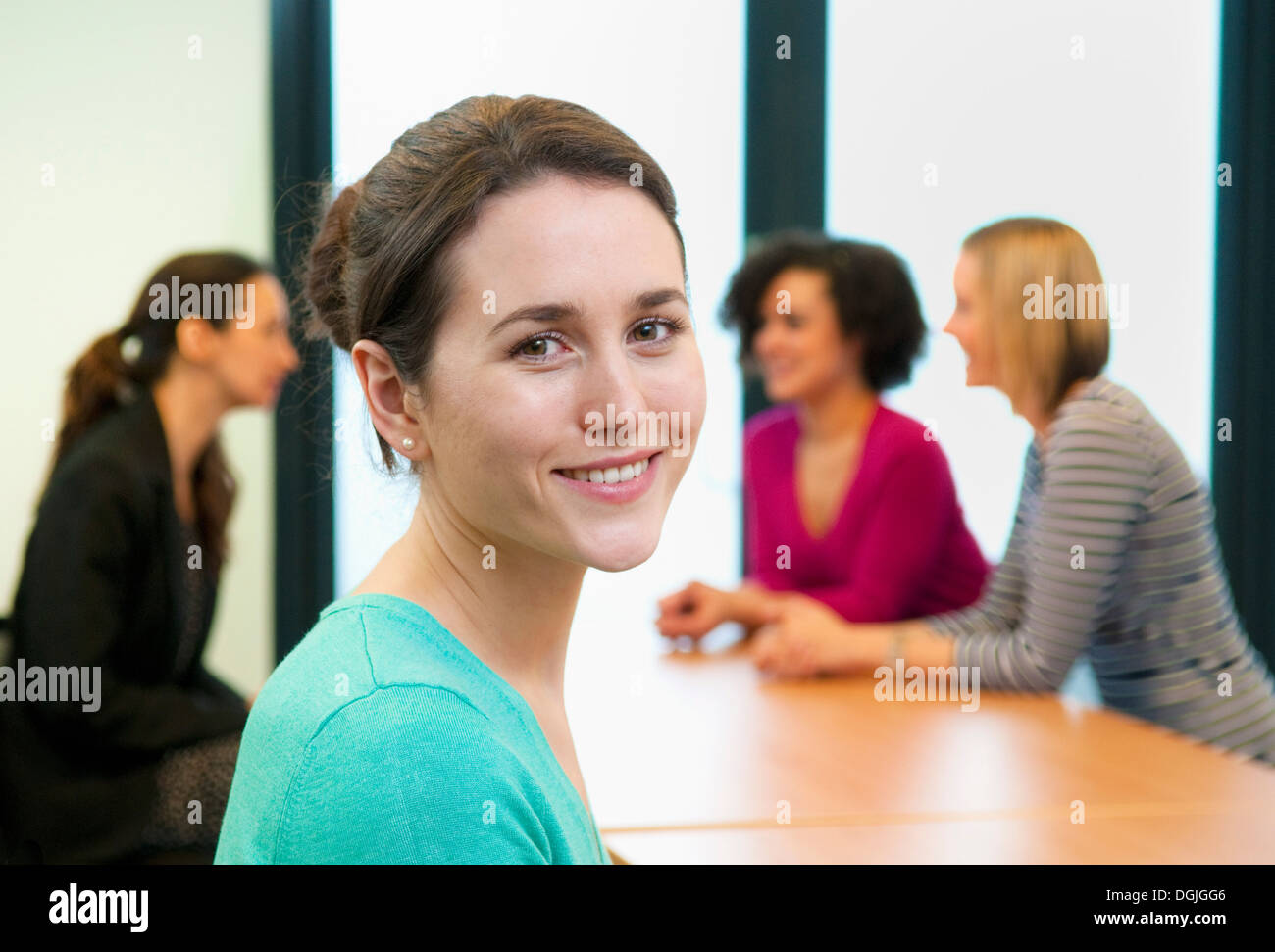 Junge Frau im Büro mit Kollegen im Hintergrund Stockfoto