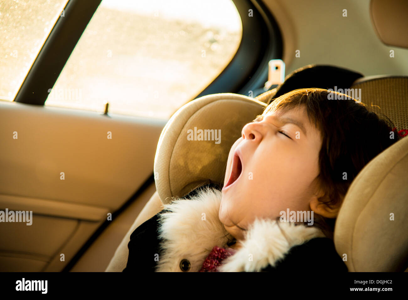 Junges Mädchen mit Augen geschlossen Gähnen im Auto Stockfoto