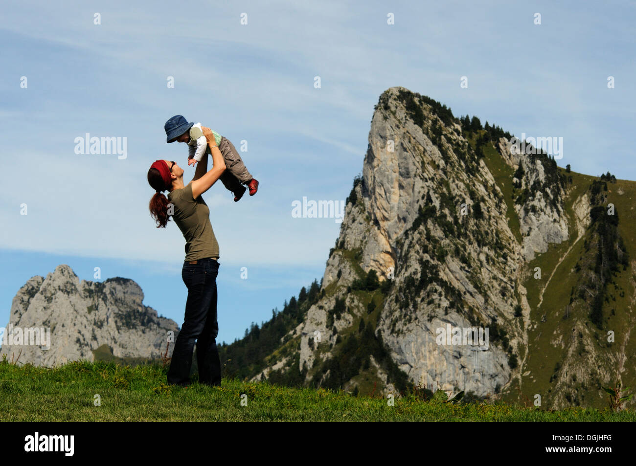 Eine junge Mutter hält ihr Baby in die Luft in den Alpen Stockfoto