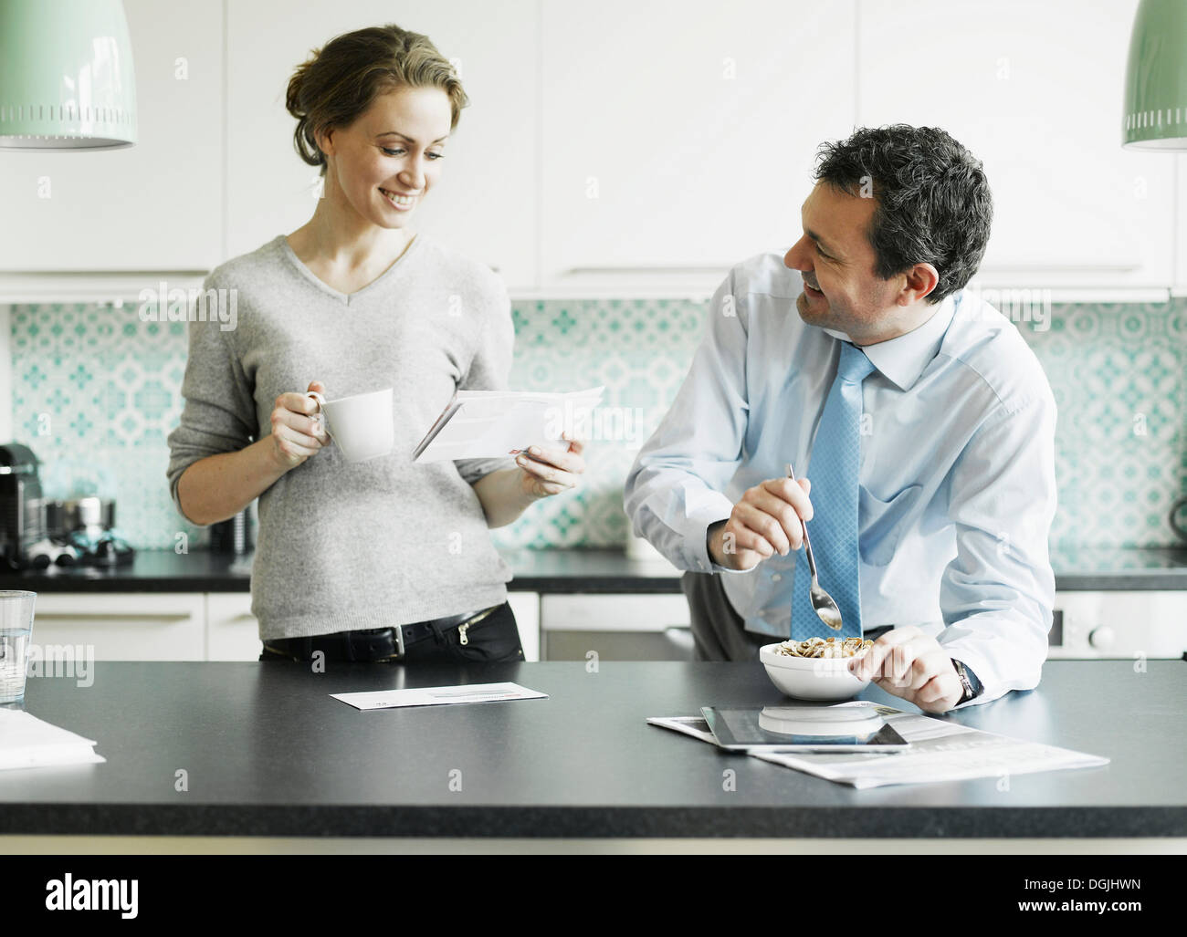 Mitte erwachsenen Frau liest Dokument über das Frühstück mit Ehemann Stockfoto