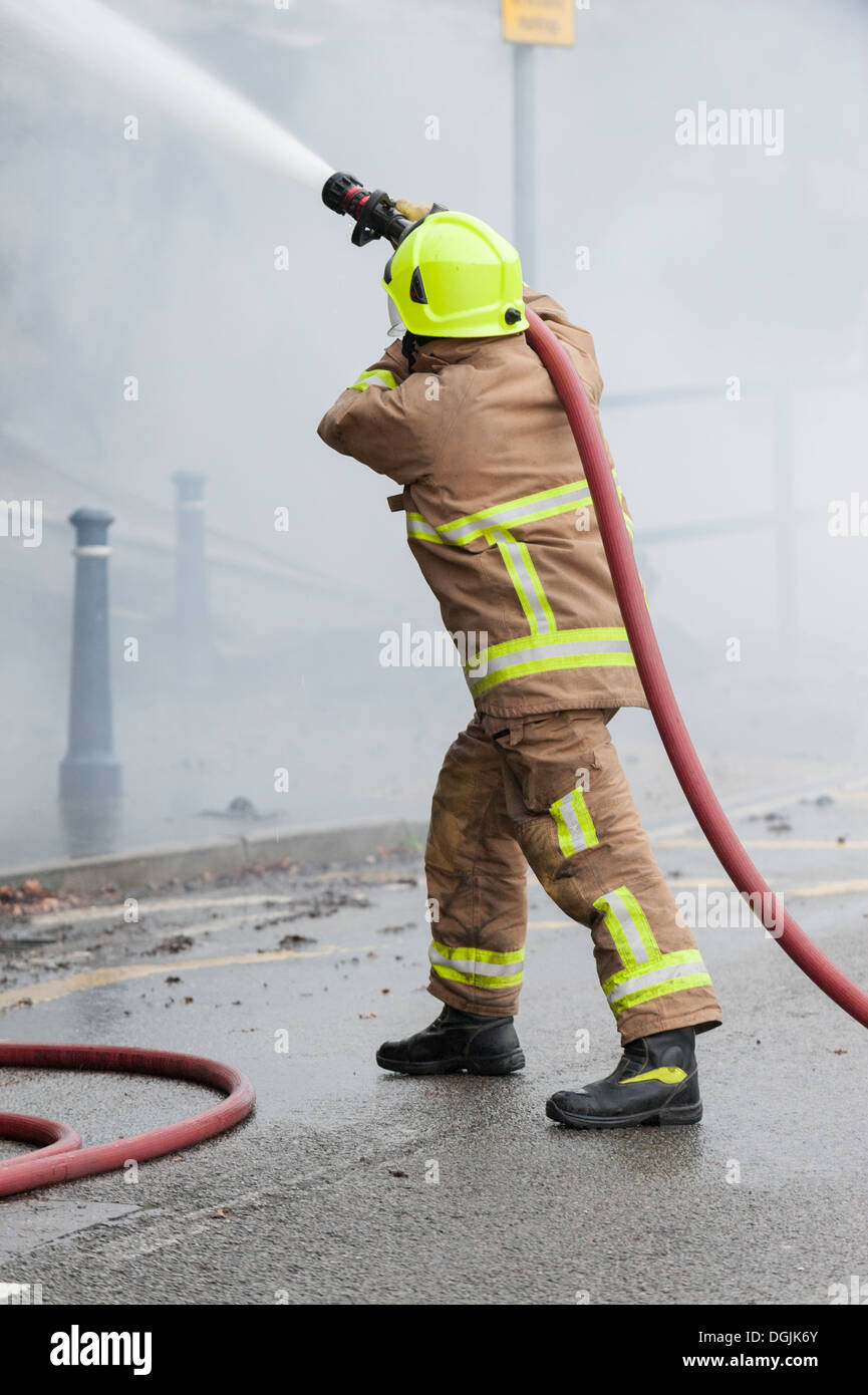 Ein Mitglied der Feuerwehr Essex befasst sich ein Feuer mit einem Schlauch. Stockfoto